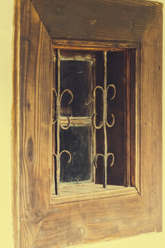 Rustic wooden window with wrought iron bars, evoking a sense of nostalgia and vintage charm.