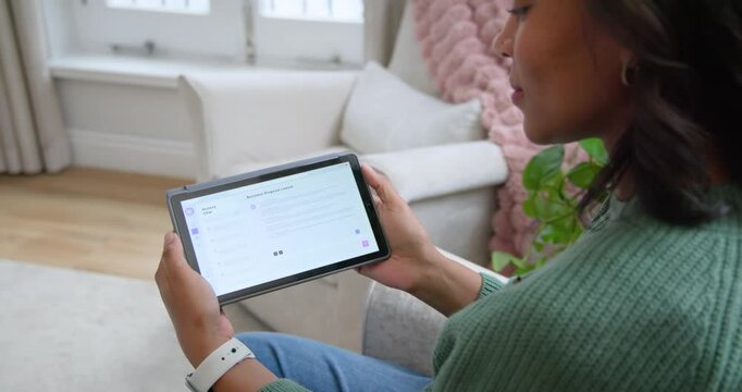 African American woman lifting tablet, angling toward face and reading by window, copy space
