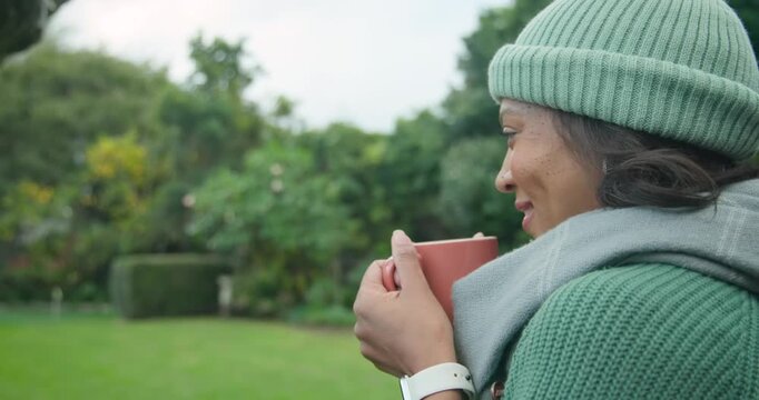 Camera moving closer, African woman holding mug in garden, turning, making eye contact, copy space
