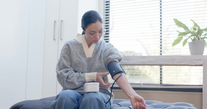 African American woman in sweater placing cup down picking meter fitting cuff checking BP by blinds
