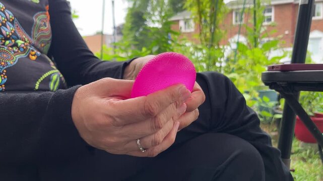 two hands, stress toy, relaxation, stress relief, mental health, wellness, mindfulness, squeeze toy, sensory object, pink toy, holding, squeezing, tactile, flexible, fidget toy, outdoor, garden, backy