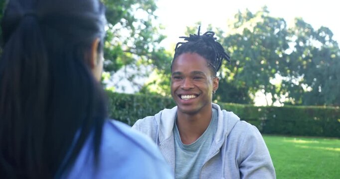 African American friends exchanging playful right-hand high-five after his warm smile on sunny lawn