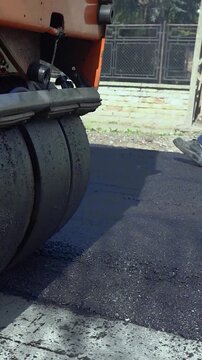Orange Combination Roller Compacting Hot Asphalt Road Construction Slow Motion. Heavy machinery driving backward on fresh tarmac during city street reconstruction. Great for roadwork concepts.