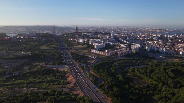 drone shot of congested highway traffic flowing towards Lisbon city center, showcasing Almada district, Christ statue monument and famous 25 de Abril bridge infrastructure