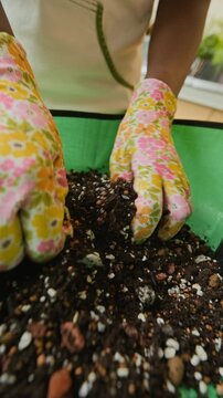 Vertical video of woman mixing potting soil with hands in floral gloves. Footage suits gardening tutorials, plant care ads, or sustainable lifestyle promos