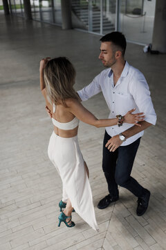 Couple dancing salsa in a modern hall practicing partner dance steps, connection and movement during a casual dance lesson