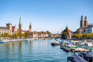 This picturesque scene captures the Limmat River flowing through the historic center of Zurich, Switzerland, framed by iconic church spires and docked boats. © Agnieszka Gaul