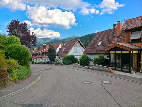 germany, scenic road through charming elzach black forest village surrounded by forested mountains beneath brilliant deep blue summer sky landscape