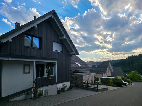 germany, beautiful newly built houses in elzach black forest village glowing beneath radiant sunset sky creating welcoming modern countryside atmosphere