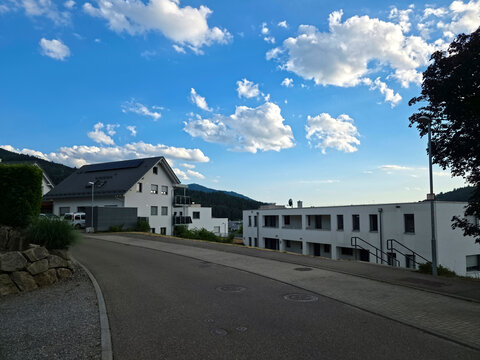 germany, beautiful newly built houses in elzach black forest village beneath glowing sunset sky with hoernleberg mountain chapel overlooking the valley