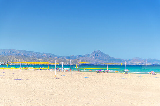 Playa de San Juan beach in Alicante city, sports area courts with volleyball net on Muchavista sandy beach of Mediterranean Sea coast Costa Blanca in sunny summer day, Puig Campana mountain, Spain