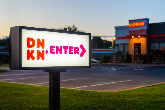 New Hartford, Jul 7, 2026: Night selective focus view of Dunkin&rsquo; restaurant, featuring illuminated entrance signage, an American coffee & baked goods retailer with over 13,000 locations worldwide