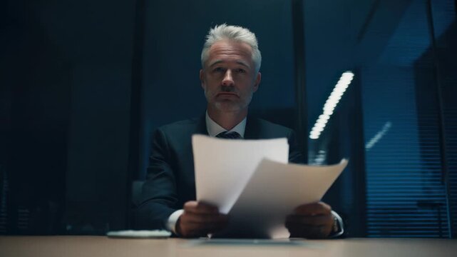 Business meeting in a dimly lit office as a man reviews important documents at night