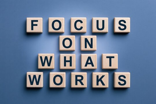 Focus on what works phrase written with wooden tiles on blue background