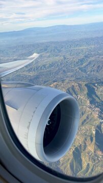 Aerial view of Los Angeles during landing, seen through an airplane window. Expansive cityscape, urban grid and clear skies capture the excitement of arriving in Southern California.
