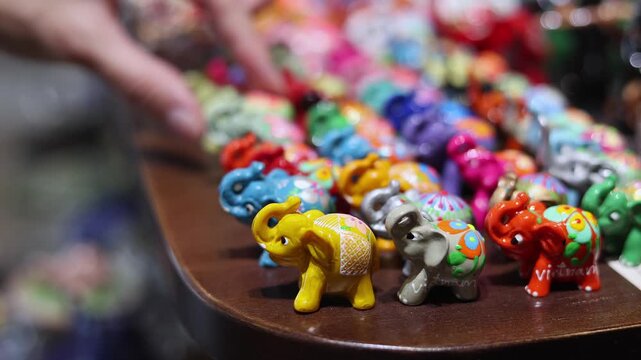 Colorful small elephant figurines displayed at Vietnamese souvenir shop in Nha Trang, Vietnam. Row of cute ceramic and wooden Asian elephant statues on table of local gift market. Tourism concept.