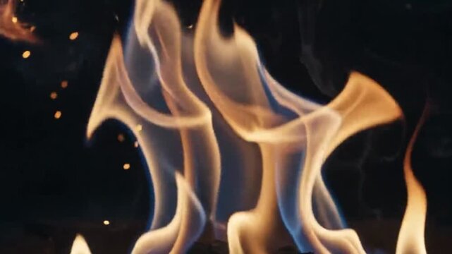 Closeup of vibrant fire flames with glowing sparks rising against a dark background