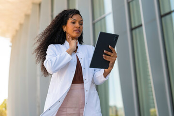 Fototapeta premium Doctor palpating neck while using digital tablet for telehealth video consultation