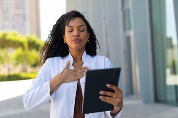 Obraz premium Female doctor finding calm and relief outdoors holding tablet