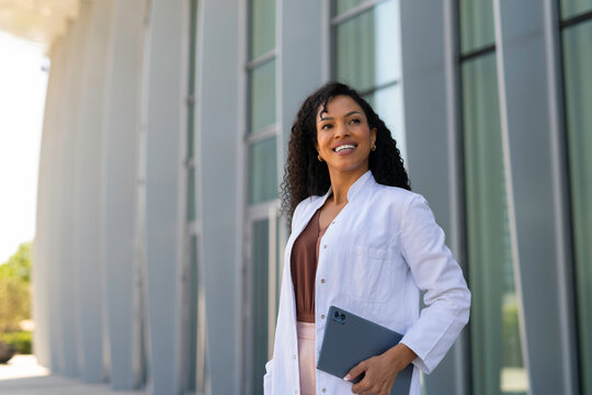 Female doctor holding digital tablet smiling outdoors