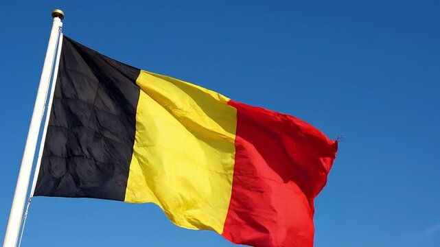National flag of belgium waving against a clear blue sky