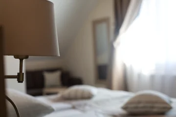 Cozy hotel room with soft bedding and natural light from window © photopixel