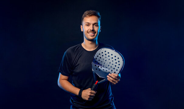 Padel tennis player with racket. Man athlete with paddle racket on court with neon colors. Sport concept. Download a high quality photo for the design of a sports app or betting site.