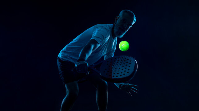 Padel tennis player with racket. Man athlete with paddle racket on court with neon colors. Sport concept.