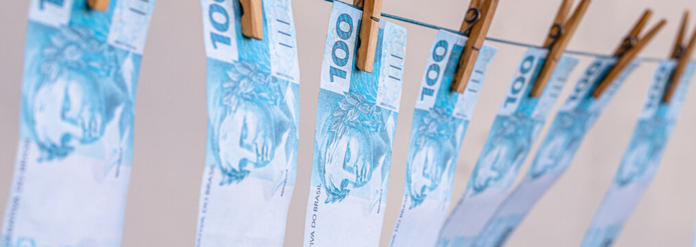 Money laundering concept featuring Brazilian banknotes hanging on a clothesline; corruption, financial scandal, theft.