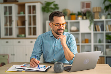 Man working remotely at home office desk checking data