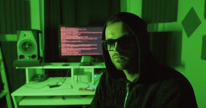 Hooded man pulling up his hood and staring directly into the camera, representing hacking, cybercrime, anonymity, and digital security threats.
