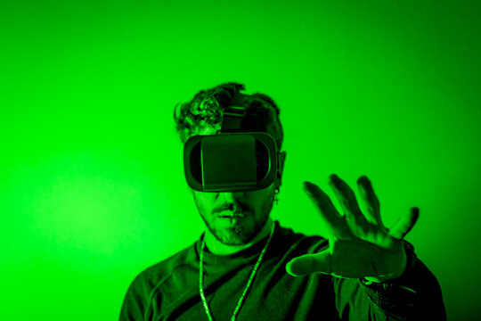 Young man immersing in virtual reality using vr headset in green light