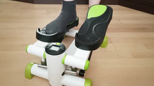 Black shoes on mini stepper pedals during exercise routine, dynamic foot placement showing active cardio training session indoors.