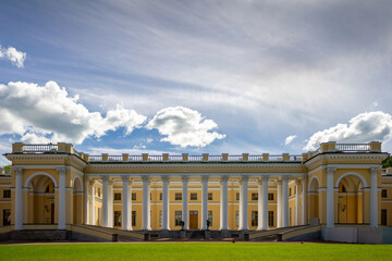 View of Alexander Palace in Alexander Park, Pushkin, Saint Petersburg, Russia, on a sunny summer day. Historic neoclassical imperial residence with elegant colonnade, green lawn, and dramatic clouds u © vshq