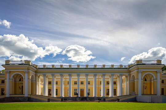 View of Alexander Palace in Alexander Park, Pushkin, Saint Petersburg, Russia, on a sunny summer day. Historic neoclassical imperial residence with elegant colonnade, green lawn, and dramatic clouds u