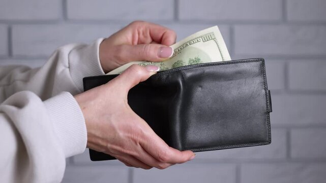 A woman counts money. A woman's hand pulls a new-style hundred-dollar bill out of her wallet