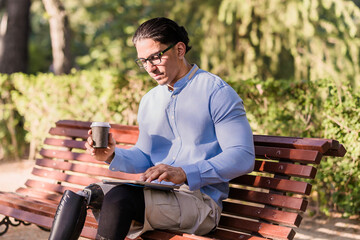 Fototapeta premium Latino man with prosthetic leg using tablet in park