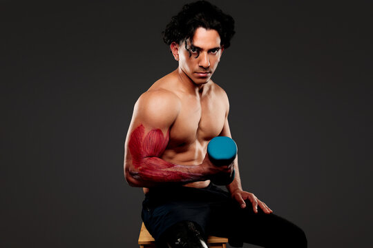 Latino man lifting dumbbell visualizing bicep anatomy for strength