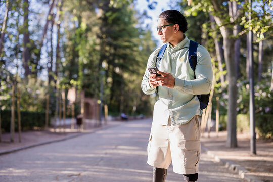 Latino man with disability using phone outdoors