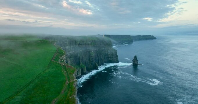 Aerial flyby of Cliffs of Moher coastline with sea stack and drifting fog, Ireland