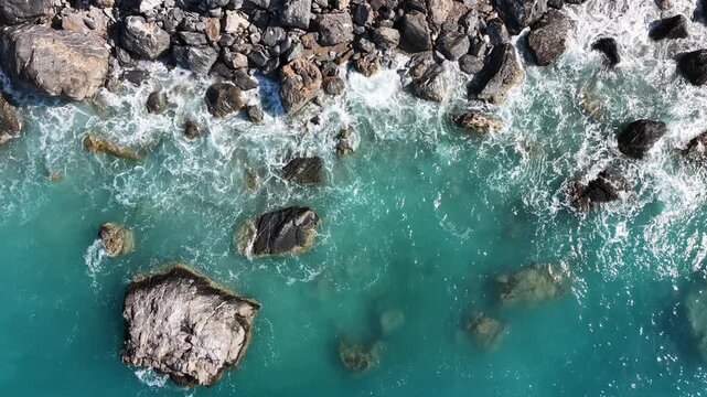 erial top-down view of turquoise ocean waves crashing against rocky coastline, 4K drone footage.