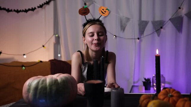 Cute Little Girl Blowing Out A Candle In A Halloween Decorated Room