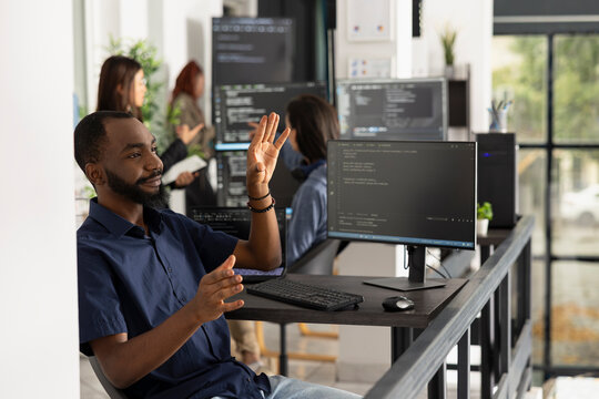 Male programmer interacts with invisible holographic interface in office. Developer explores augmented reality and advanced human computer interaction while working on innovative technology solutions.