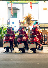 Three red scooters for rent parked neatly outside a warmly lit café on a tiled sidewalk © Mikhail Mishchenko