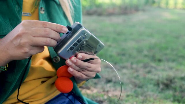 Hands connecting vintage headphones to cassette player outdoors - Retro audio and nostalgia lifestyle trend