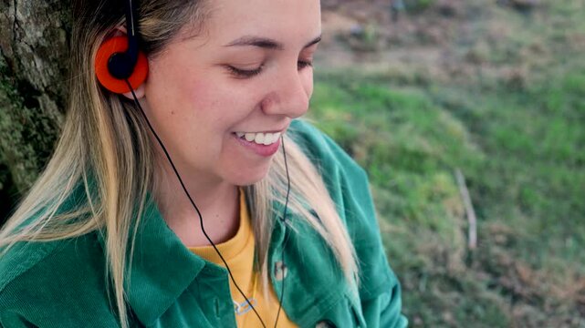 Happy woman listening music with vintage headphones at park city - Nostalgia lifestyle trend