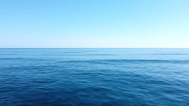 A vast expanse of blue ocean meets a bright, cloudless sky in serene harmony