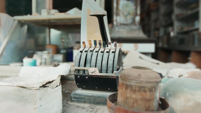 Vintage antique check writing machine sits on dusty workbench in abandoned workshop, surrounded by rusty cans and old papers, with soft natural light filtering through dirty windows in background.