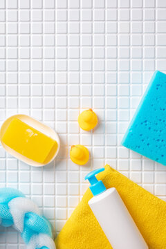 Top view of baby bath accessories and rubber ducks on white mosaic tiles with top copy space