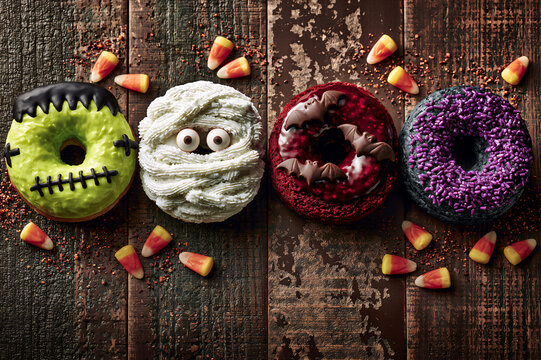 Overhead view of a row of Halloween monster donuts on a distressed dark table